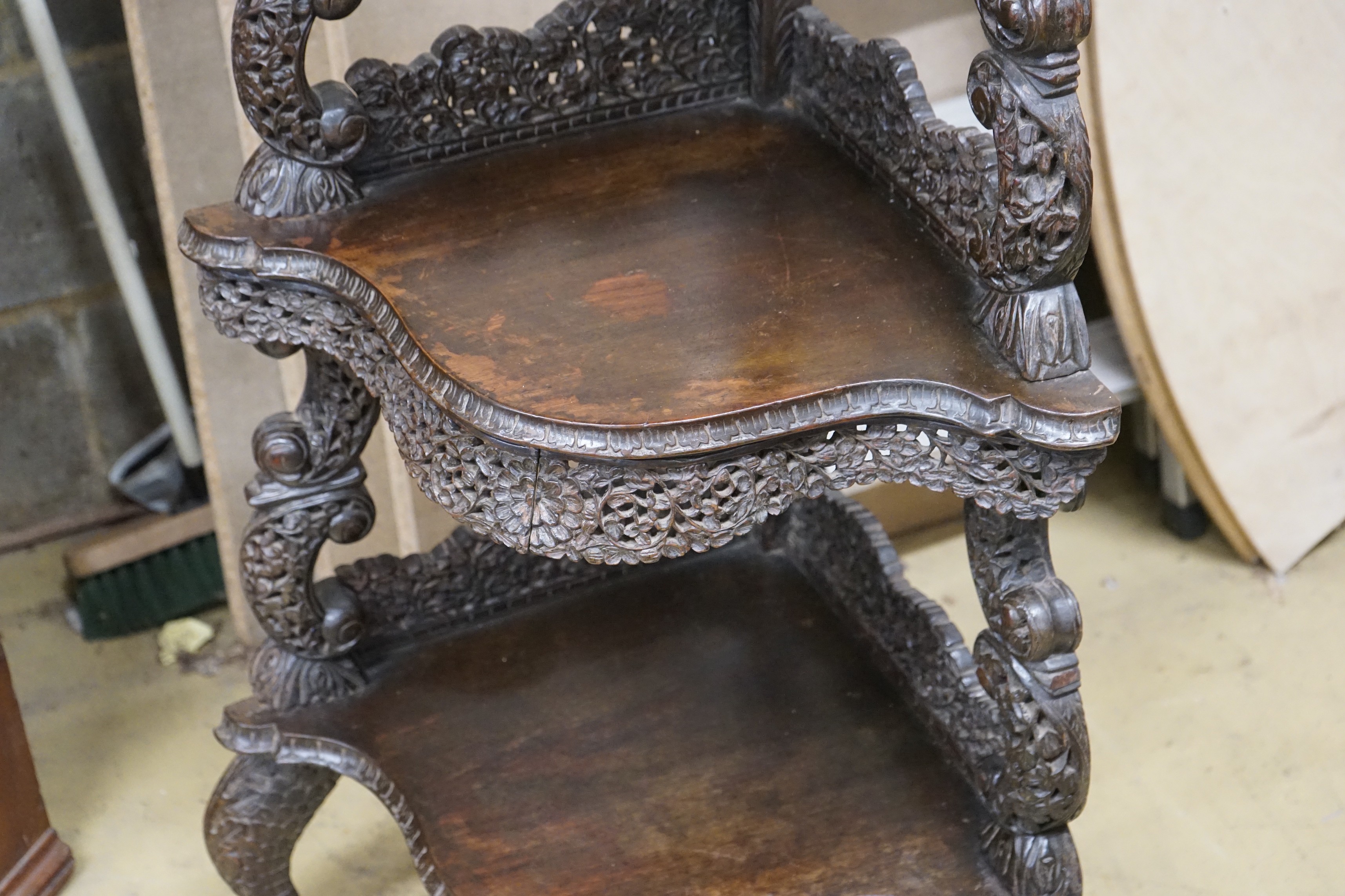 A 19th century Burmese carved hardwood serpentine corner whatnot, width 60cm, depth 42cm, height 153cm